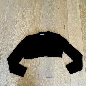 This is a cropped cardigan. It is navy blue and is cut off at the edges.